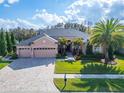 Beautiful home with a large yard, a three-car garage, lush landscaping, and a brick-paved driveway at 2903 Marble Crest Dr, Land O Lakes, FL 34638