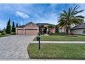 Charming home with a three-car garage, lush landscaping, and a brick-paved driveway at 2903 Marble Crest Dr, Land O Lakes, FL 34638