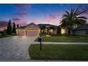 Charming home with a three-car garage, lush landscaping, and a brick-paved driveway at 2903 Marble Crest Dr, Land O Lakes, FL 34638