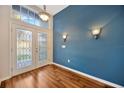 Bright foyer showcasing hardwood flooring, a stylish light fixture, and a charming, colored accent wall at 3339 Brenford Pl, Land O Lakes, FL 34638