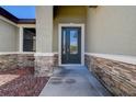 Close-up of the front door with decorative glass, a stone facade, and a landscaped walkway at 624 Tierra Dr, Spring Hill, FL 34609