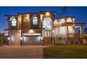 Elegant two-story home with a three-car garage and lush landscaping illuminated at dusk at 124 Leeward Is, Clearwater Beach, FL 33767