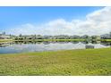 Scenic view of a tranquil pond reflecting nearby homes under a partly cloudy blue sky at 16631 Mooner Plank Cir Cir, Wimauma, FL 33598