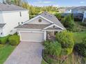 Aerial view of the home featuring a paver driveway, two-car garage, landscaped front yard and mature trees at 17628 Breakaway St, Land O Lakes, FL 34638