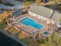 Aerial view of a sparkling community pool, sundeck, and jacuzzi surrounded by lush landscaping and comfortable lounge chairs at 3300 Haviland Ct # 304, Palm Harbor, FL 34684