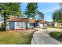 Charming blue home with a well-manicured front yard, mature trees, and a welcoming pathway to the entrance at 3544 Landale Dr, Holiday, FL 34691