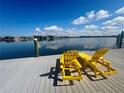 Relaxing waterfront view from the dock with two yellow Adirondack chairs under a clear blue sky at 4941 Waterside Dr, Port Richey, FL 34668