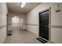 Well-lit hallway with neutral colors, leading to a black entry door with a welcome mat at 501 Knights Run Ave # 1203, Tampa, FL 33602