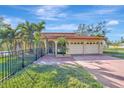 Inviting two-story home with a red tile roof, three-car garage, and tropical landscaping at 612 Montezuma Dr, Bradenton, FL 34209