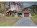 Charming single story home with mature trees, a red trim and a spacious driveway leading to an attached garage at 8547 Horizon Ln, Hudson, FL 34667