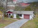 Charming single story home with mature trees, a red trim and a spacious driveway leading to an attached garage at 8547 Horizon Ln, Hudson, FL 34667