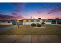 Charming single-story home featuring well-maintained landscaping, a carport, and a neatly kept front lawn at dusk at 1531 Council Dr, Sun City Center, FL 33573