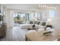 Bright and airy living room with hardwood floors, neutral decor, and sliding doors to an outdoor patio at 18483 Green Garden Ct, Venice, FL 34293