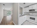 Bright kitchen with white cabinets and stainless steel appliances, adjacent to a cozy living area at 2914 Westmoreland Ct, New Port Richey, FL 34655