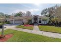 Charming single-story home featuring a three-car garage, lush landscaping, and a well-manicured lawn at 3037 Crest Dr, Clearwater, FL 33759