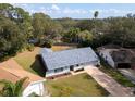 Aerial view of a single-story home with a gray roof surrounded by lush landscaping in a quiet neighborhood at 3373 Brodie Way, Palm Harbor, FL 34684