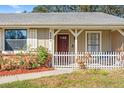 Welcoming front entrance with a red door, white picket fence, and landscaped garden at 8449 Valmora St, Spring Hill, FL 34608