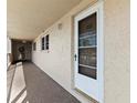 Exterior view of condo unit 203 with storm door along a shared walkway at 9950 62Nd N Ter # 203, St Petersburg, FL 33708