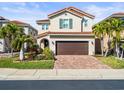 Beautiful two-story home featuring a brick driveway, lush landscaping, and a classic red tile roof at 10193 Grand Oak Cir, Madeira Beach, FL 33708