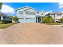 Two-story home with blue exterior, well-manicured landscaping, and brick paver driveway at 18329 Roseate Dr, Lutz, FL 33558