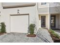 Clean exterior view of a modern townhome featuring a one-car garage, minimal landscaping, and a gray paver walkway at 25993 Woven Wicker Bnd, Lutz, FL 33559