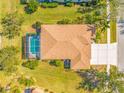 Aerial view of the home featuring screened in pool, driveway and mature trees at 833 Seminole Sky Dr, Ruskin, FL 33570