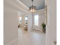 Bright hallway with decorative lighting fixture, white walls, and light-colored wood floors leading to the front door at 9273 Highland Hills Dr, Hudson, FL 34667