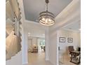 Bright hallway with decorative lighting fixture, white walls, and light-colored wood floors leading to the dining room at 9273 Highland Hills Dr, Hudson, FL 34667