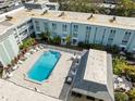 Aerial view of condo building with a refreshing community pool and lounge area, surrounded by lush landscaping at 1706 Belleair Forest Dr # 348, Belleair, FL 33756