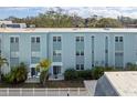 Back of a charming condo building featuring a private patio, lush landscaping, and a white picket fence at 1706 Belleair Forest Dr # 348, Belleair, FL 33756