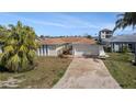 A well-maintained single-story home with a two-car garage, manicured lawn, and mature landscaping provides great curb appeal at 13614 Evelane Dr, Hudson, FL 34667