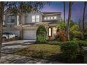 Charming two-story home with an attached garage, front lawn, and mature landscaping at dusk at 14541 Mirabelle Vista Cir, Tampa, FL 33626