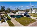 Turquoise home showcasing a large front yard, a covered carport, and convenient access to an additional garage at 3774 Arkansas Ne Ave, St Petersburg, FL 33703
