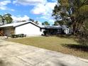 Charming single-story home featuring a lush green lawn and mature trees at 39349 & 39343 Rusbe Dr, Zephyrhills, FL 33540