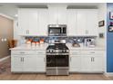 Modern kitchen featuring stainless steel appliances, white cabinets, and stylish backsplash at 17308 Holly Well Ave, Wimauma, FL 33598