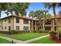 Inviting condo exterior features a terracotta tile roof and manicured lawn with lush tropical landscaping at 1003 Hammock Pine Blvd # 1003, Clearwater, FL 33761