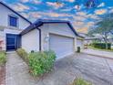 Close up of townhome featuring a well-maintained lawn, landscaping, and an attached two-car garage with a wide driveway at 11212 Port Douglas Dr, New Port Richey, FL 34654
