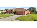 Single-story home with a two car garage and a long driveway showcasing the lawn and landscaping at 13481 Pullman Dr, Spring Hill, FL 34609