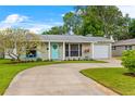 Inviting single-story home with a circular driveway, manicured lawn, and a charming teal front door at 1859 Nevada Ne Ave, St Petersburg, FL 33703