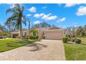 Beautiful single-story home with a paver driveway, lush landscaping, and an attached two-car garage at 2218 Mayfield Palms Ln # 323, Sun City Center, FL 33573