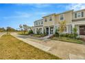 Charming townhomes featuring manicured lawns, and sidewalks, set against a clear blue sky and lush greenery at 5080 Avalon Park Blvd, Wesley Chapel, FL 33545