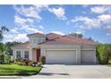 Charming single-story home featuring a clay tile roof, three-car garage, and a well-manicured lawn at 6214 45Th E Ln, Bradenton, FL 34203