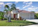 Lovely single-story home with a three-car garage, landscaped lawn, and a welcoming red front door at 6214 45Th E Ln, Bradenton, FL 34203