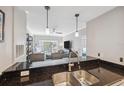 Bright kitchen with breakfast bar, stainless sink, granite countertops, and pendant lighting overlooking the living space at 800 S Dakota Ave # 323, Tampa, FL 33606