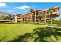 Exterior view of the building with balconies, tropical landscaping, and lush green lawn at 1060 Pinellas Bayway S # 103, St Petersburg, FL 33715