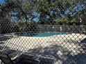 Community pool surrounded by a fence, sun loungers and mature trees at 11723 Raintree Village Blvd # B, Temple Terrace, FL 33617