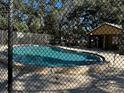 Community pool surrounded by a fence, sun loungers and mature trees at 11723 Raintree Village Blvd # B, Temple Terrace, FL 33617