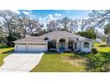 Spacious single-story home with three-car garage, lush lawn, and beautiful landscaping at 13855 Rudi Loop, Spring Hill, FL 34609