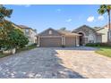 Exterior of house with beautiful landscaping and a three-car garage, brick paved drive at 2037 Blue River Rd, Holiday, FL 34691