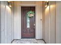 Close-up of the wooden front door with a glass window, a seasonal wreath, and two sconce lights at 2151 E Leewynn Dr, Sarasota, FL 34240